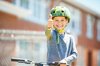 Un bambino con casco e bicicletta sorride verso l’obiettivo con il pollice alto