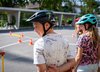 Trois enfants attendent leur tour en souriant sur le parcours vélo