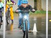 Un enfant fait du vélo sous la pluie