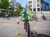 Un élève effectue un parcours à vélo sur la place de l’école. Il se concentre pour positionner correctement la balle.