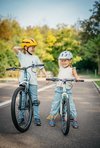 Deux fillettes au visage souriant essaient de garder l’équilibre à vélo