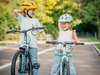 Deux fillettes au visage souriant essaient de garder l’équilibre à vélo